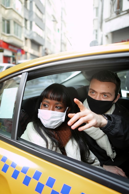 Turistas masculinos y femeninos en un taxi apuntando a algo