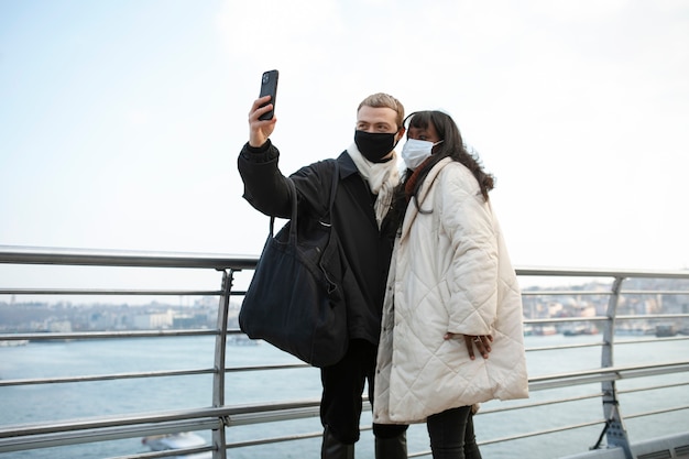 Turistas masculinos y femeninos tomando un selfie al aire libre con su teléfono inteligente