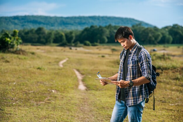 Los turistas masculinos se paran y miran el mapa en el césped.