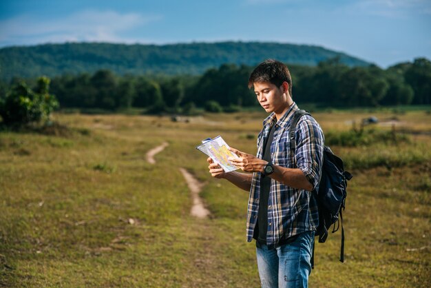 Los turistas masculinos se paran y miran el mapa en el césped.