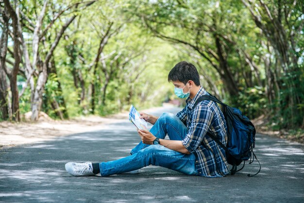 Los turistas masculinos se sientan y miran el mapa en el camino.