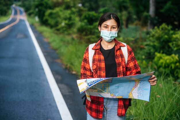 Las turistas se paran y miran el mapa en el camino.