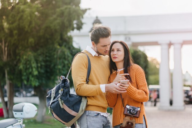 Turistas preocupados de pie en el parque con smartphone y mochila