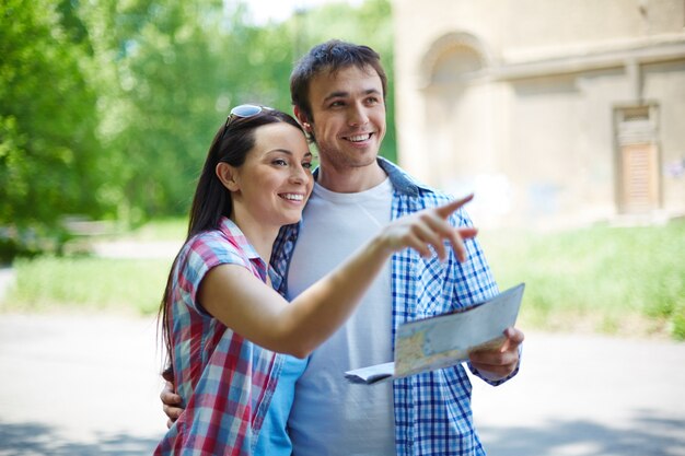 Turistas sonrientes haciendo turismo en la ciudad con un mapa