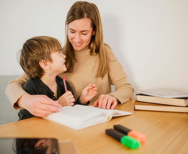 Foto gratuita tutor femenino enseñando a niño en casa