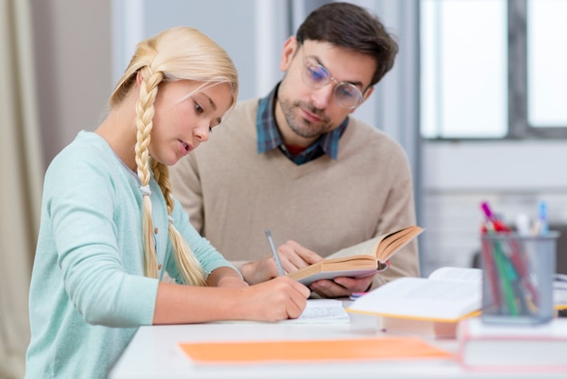 Tutor y niña en casa escribiendo