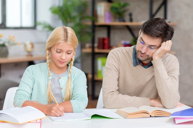 Tutor y niña en casa haciendo la tarea