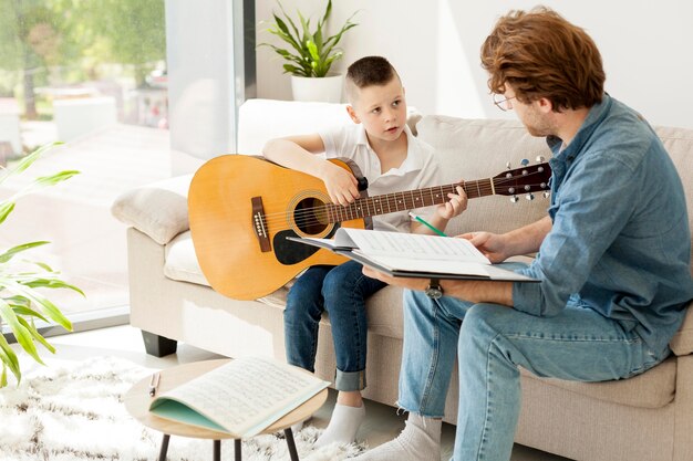 Tutor y niño aprendiendo guitarra desde casa