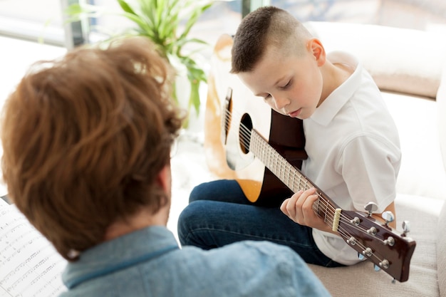 Tutor y niño aprendiendo guitarra sobre la vista del hombro