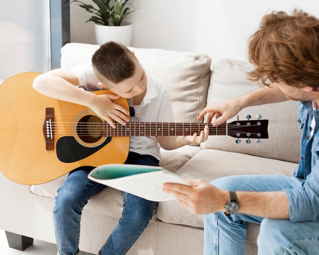 Tutor que muestra a su alumno cómo tomar la mano de la guitarra