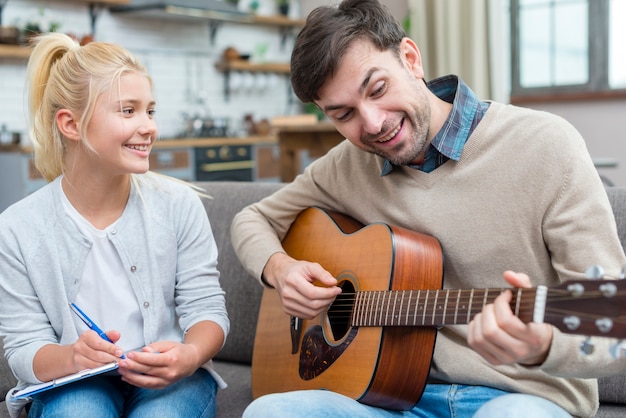 Foto gratuita tutor que muestra a su joven estudiante cómo tocar la guitarra