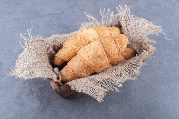 Tw croissant francés fresco en caja de madera.