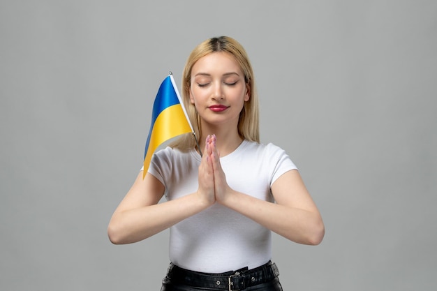 Ucrania conflicto ruso rubia linda chica con lápiz labial rojo y bandera ucraniana rezando
