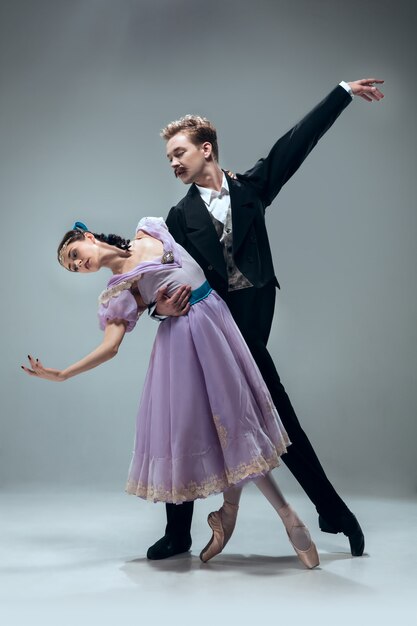 Una unidad. Hermosos bailarines de salón contemporáneos aislados en la pared gris. Artistas profesionales sensuales bailando walz, tango, slowfox y quickstep. Flexible y ingrávido.