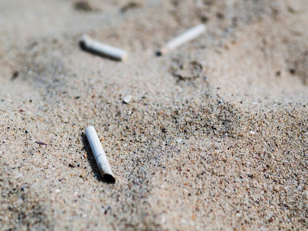 Usado colillas de cigarrillos en la arena en la playa