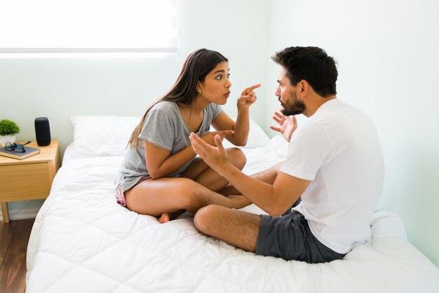 Usted es el culpable. Mujer joven resentida exigiendo algo de su novio mientras discute en el dormitorio