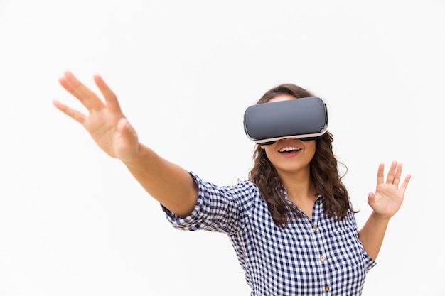 Usuario femenino positivo en gafas de realidad virtual tocando el aire y sonriendo