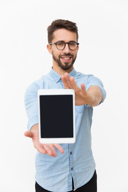 Usuario de tableta sonriente positivo que muestra la pantalla en blanco