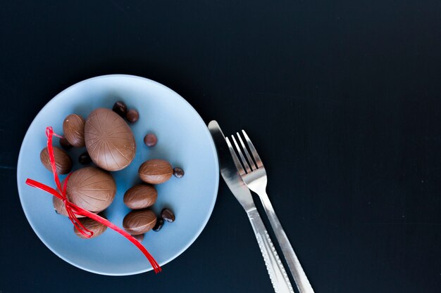 Utensilios y huevos de chocolate sobre fondo oscuro