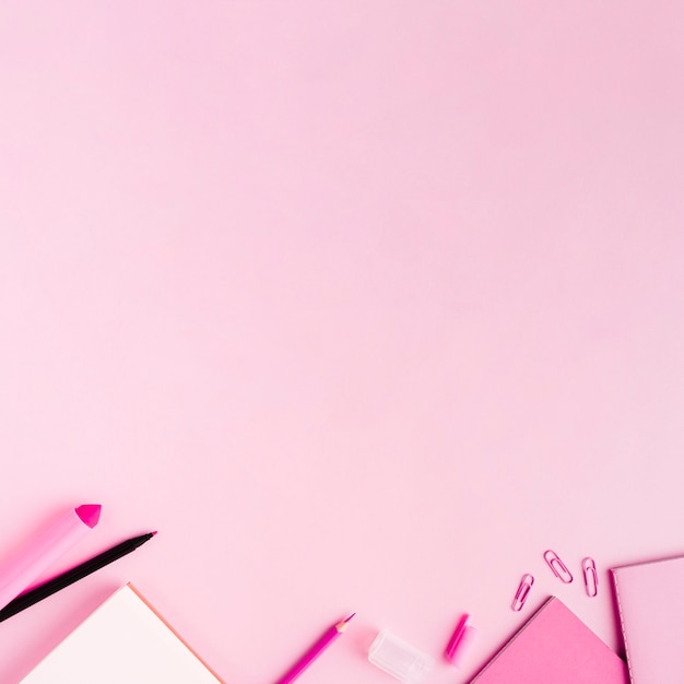 Foto gratuita utensilios de oficina rosa sobre superficie coloreada.