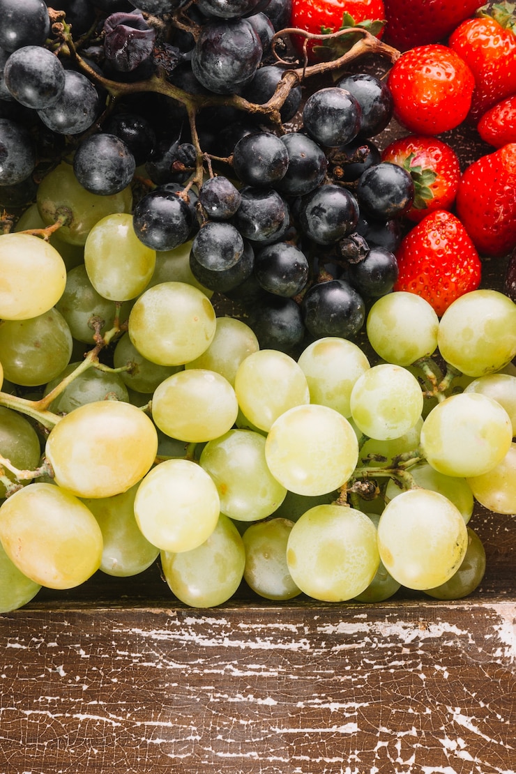 Foto gratuito uva y fresas cerca de tablón de madera