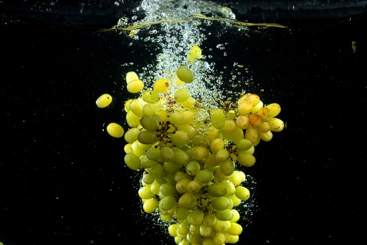Foto gratuito la uva verde salpicando en el agua en negro