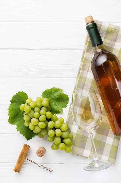 Uvas blancas y botella llena de vino.