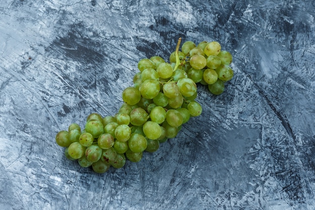 Uvas blancas laicas planas sobre fondo de mármol azul oscuro. horizontal