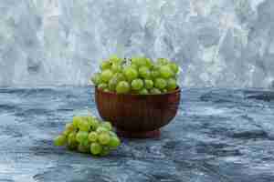 Foto gratuita uvas blancas en un recipiente sobre un fondo de mármol azul claro y oscuro. de cerca.