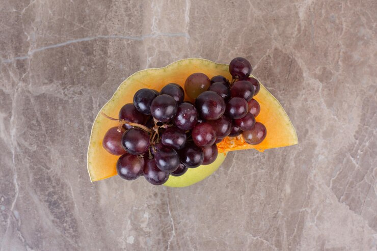 Foto gratuito uvas con calabaza amarilla sobre mesa de mármol