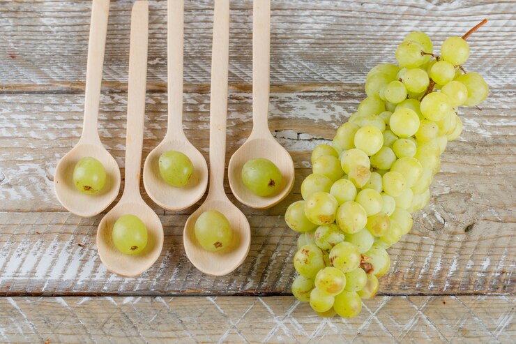 Foto gratuito uvas en cucharas sobre fondo de madera, plano laical.