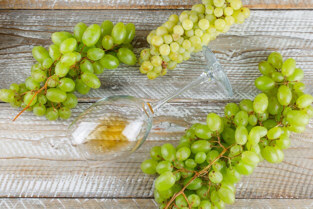 Uvas dulces con bebida plana yacen sobre un fondo de madera