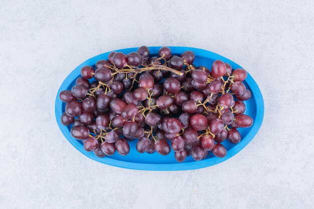 Uvas dulces frescas en placa azul sobre fondo blanco. Foto de alta calidad