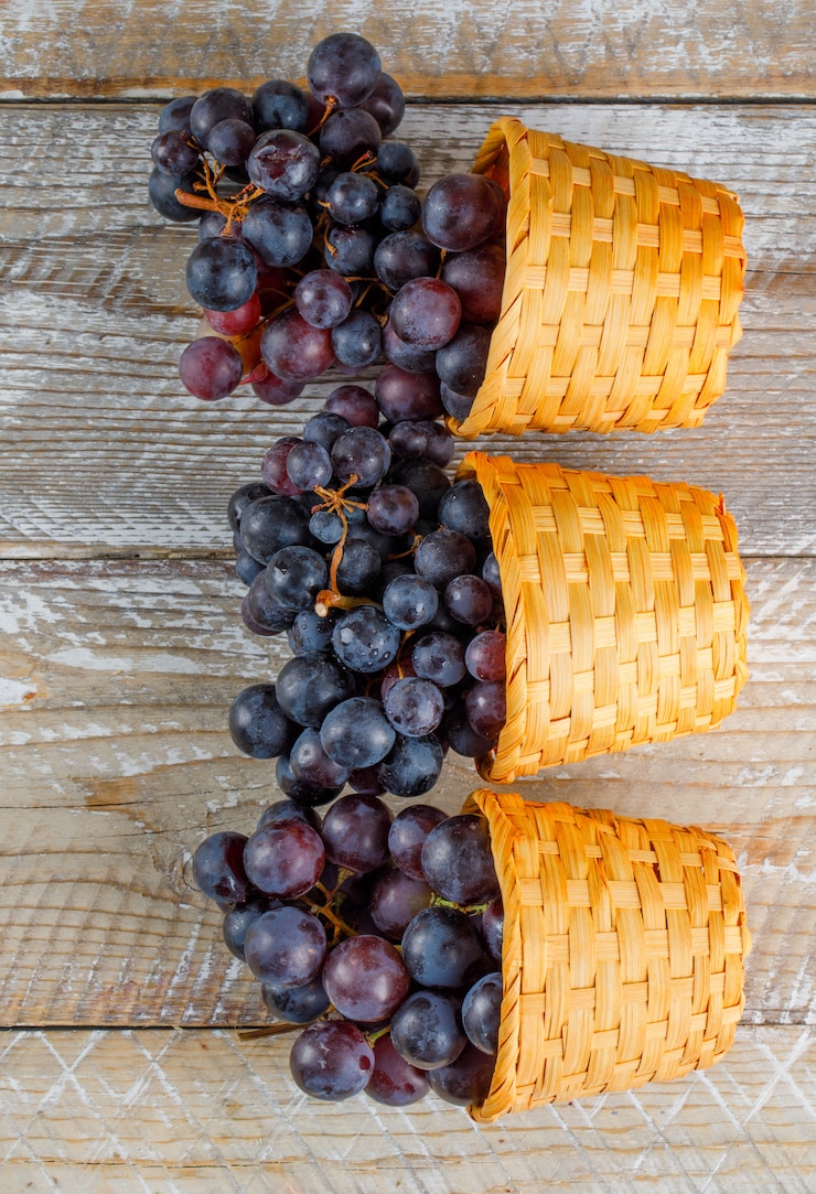 Foto gratuito uvas frescas en cestas de mimbre sobre un fondo de madera. vista superior.