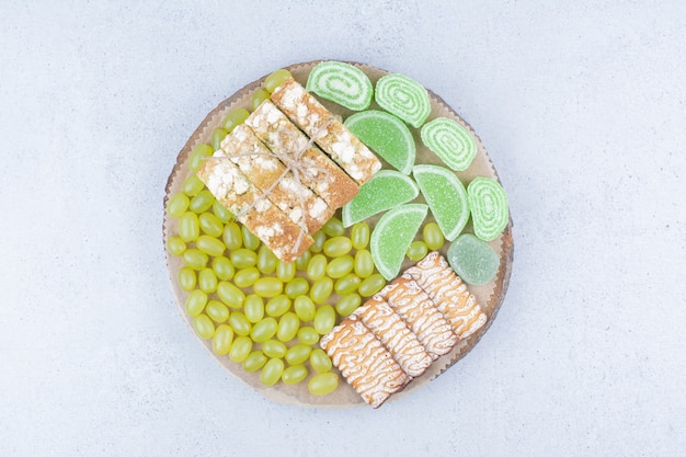 Uvas, galletas y mermeladas sobre plancha de madera.