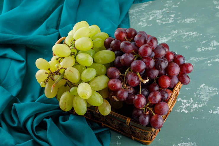 Foto gratuito uvas maduras en una canasta sobre yeso y textil. vista de ángulo alto.