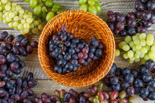 Uvas maduras en una cesta de mimbre sobre un fondo de madera. endecha plana.