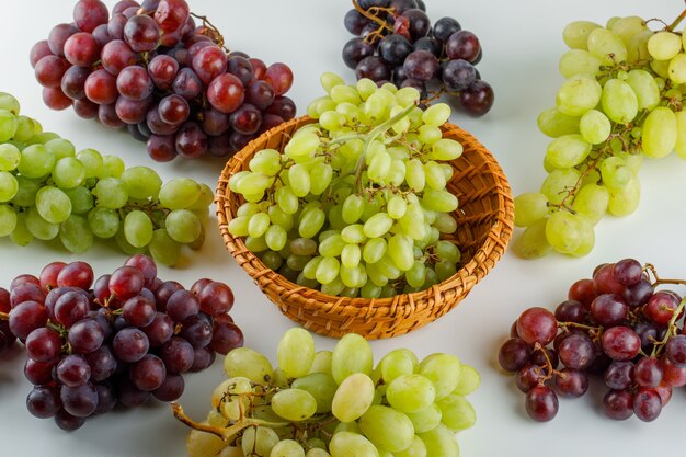 Uvas maduras en una cesta de mimbre vista de ángulo alto sobre un blanco