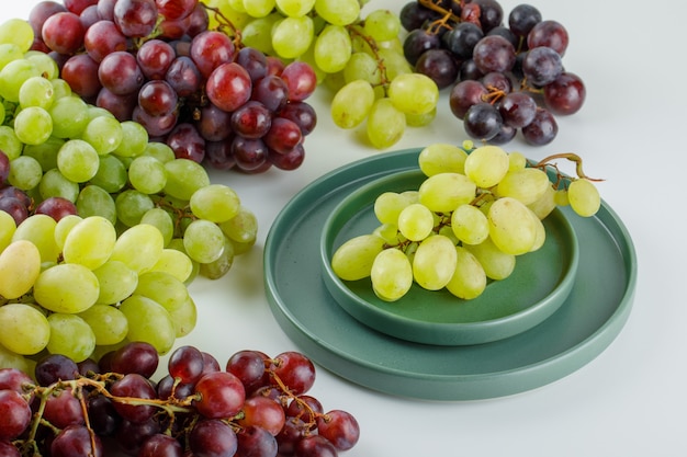 Uvas maduras en un platillo con placa vista de ángulo alto sobre un blanco