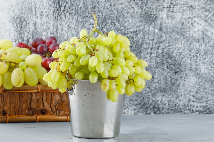 Foto gratuito uvas en mini balde y cesto sobre yeso y gris grungy.