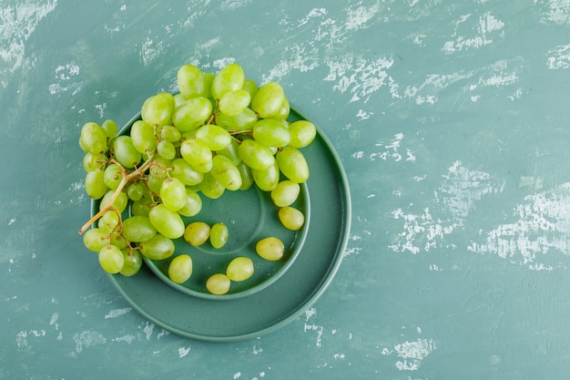 Uvas en platillo y placa plana yacían sobre un fondo de yeso