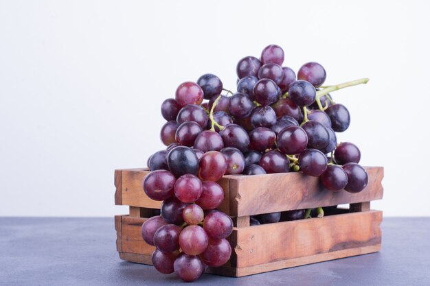 Uvas rojas en una bandeja de madera sobre superficie azul