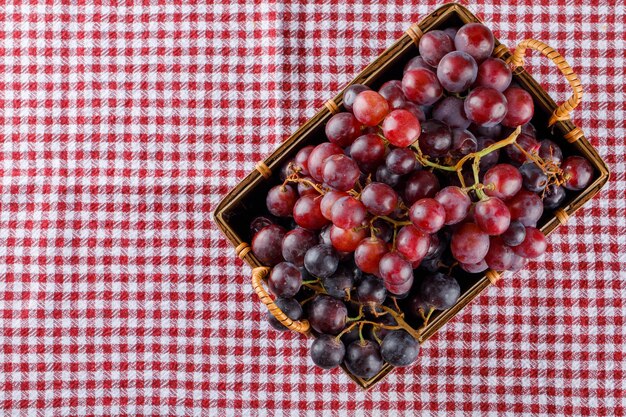 Uvas rojas en una canasta sobre tela de picnic,