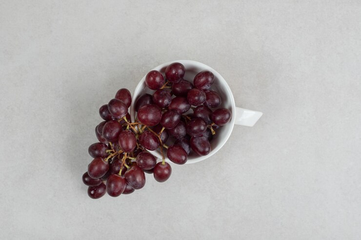 Foto gratuito uvas rojas frescas en taza blanca