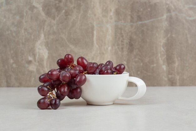 Uvas rojas frescas en taza blanca