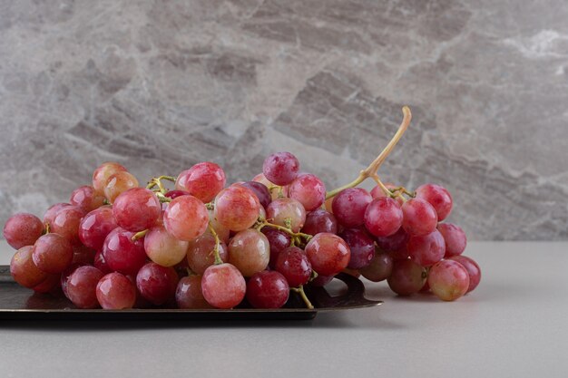 Uvas rojas en una pequeña bandeja de mármol