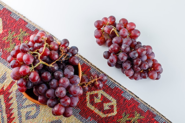 Uvas rojas en un recipiente plano yacía sobre una alfombra blanca y tradicional