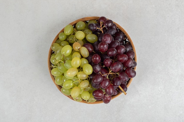 Uvas rojas y verdes frescas en canasta de madera