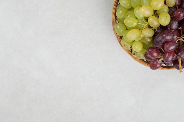 Foto gratuita uvas rojas y verdes frescas en canasta de madera