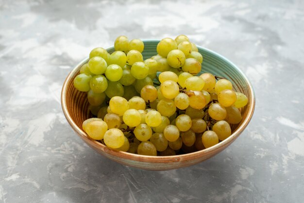 Uvas verdes frescas dentro de la placa a la luz